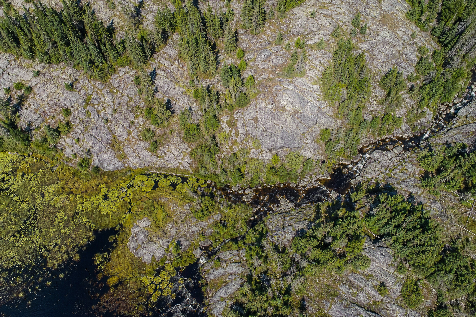 Top-down aerial view of Northern Ontario rock, stream, wetland, and forest
