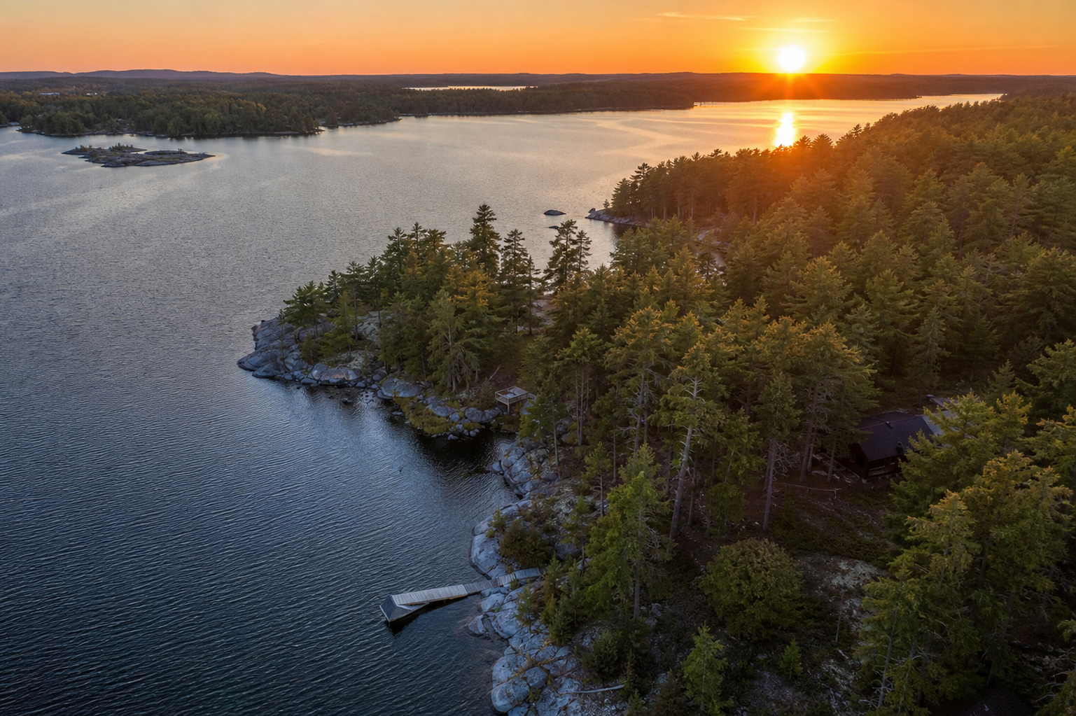 Aerial sunset view of Northern Ontario waterfront land and forest